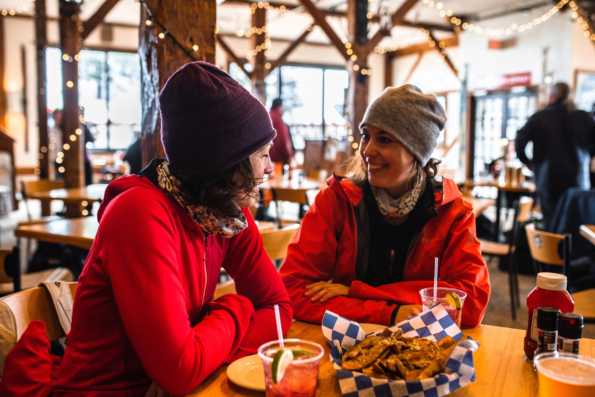 Ladies in red jackets and beanies with food and drinks at table