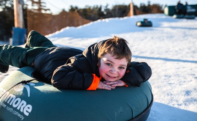 child laying on snow tube