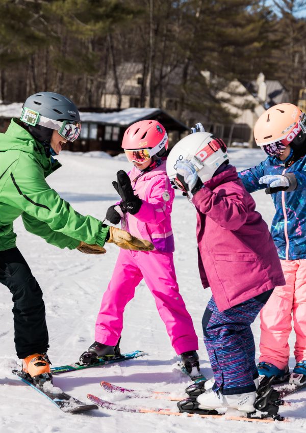 Instructor on skis with three kids learning to ski